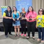 Jaciara, Marcia, Glenda, Brenda e Glaucia estão em pé sorrindo, segurando troféus e medalhas, em frente a um banner escrito Etapa Regional Sul da Copa Brasil de xadrez para deficientes visuais em clima de conquista e celebração. Classificação feminina 1 - Glenda Felippe e Silva – 4 pontos 2 - Márcia Maria Dias Lopes – 4 pontos 3 - Brenda de Paula Pires – 3,5 pontos 4 - Jaciara Marciane da Rosa – 3,5 pontos 5 - Gláucia Teixeira de Queiroz – 3 pontos